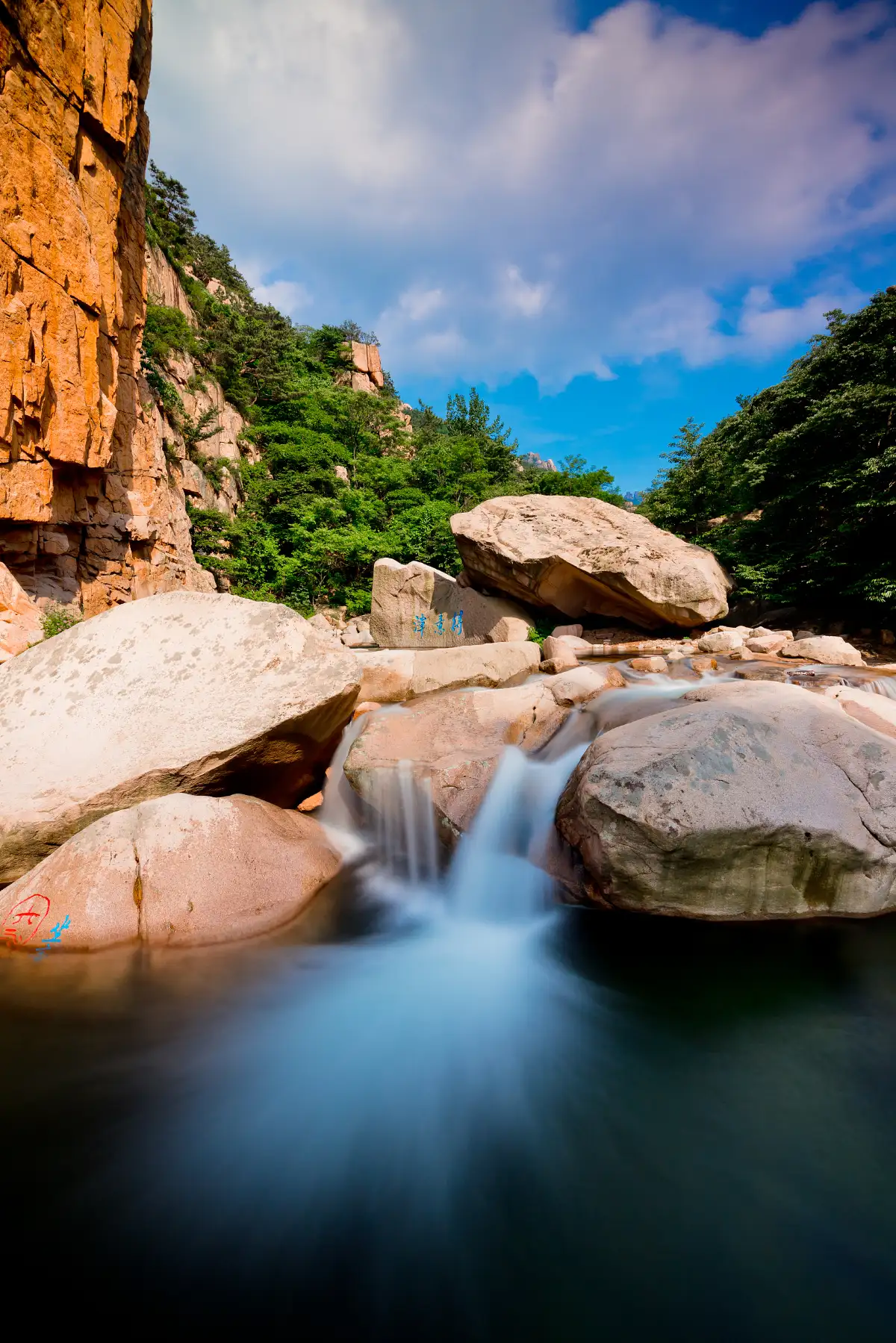 Mountain stream cascading over granite boulders in Beijiushui