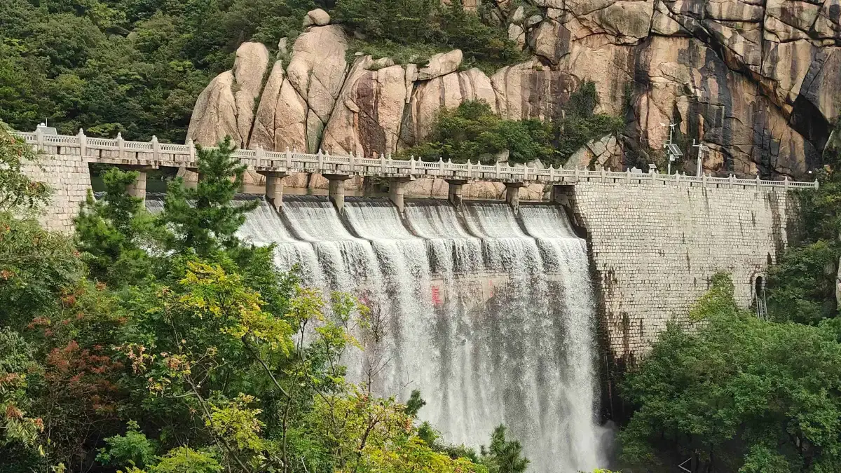 Dam waterfall beneath granite cliffs in the Laoshan valleys